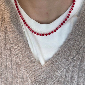 Detail of red agate beaded necklace with silver accents on a cozy knit outfit