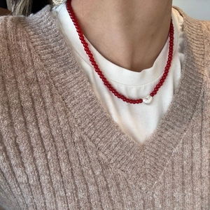 Close-up of red beaded necklace with white heart-shaped pearl pendant for women