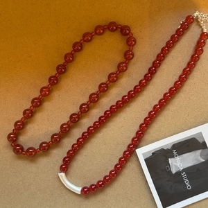 Detail of red agate beaded necklace with silver curved metal tube and adjustable clasp