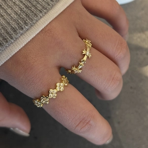 Detailed view of gold multi-layered zircon ring on model hand with a cross design