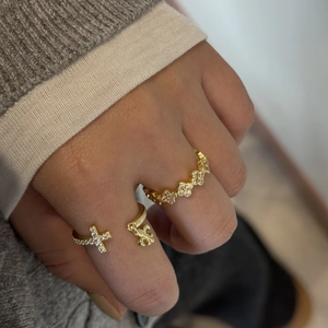 Close-up of golden zircon rings with cross and fleur-de-lis motifs on a model hand