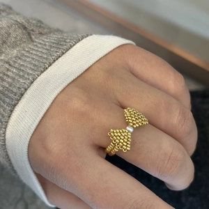 Detailed view of a handmade gold beaded bow ring with a central white pearl accent