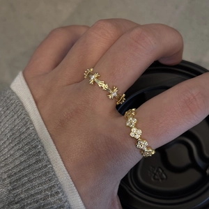 Close-up of stacked gold rings with cross pattern and zircon floral designs