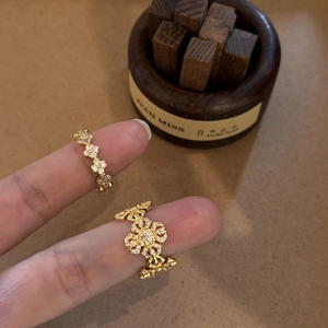 Close-up of golden floral rings with white cubic zirconia on a wood and paper base