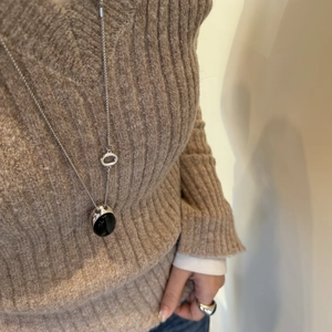 Dettaglio della collana lunga in argento con grande ciondolo ovale in pietra nera su modella
