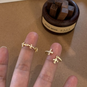 Detail of gold-plated triple rings featuring zircon-studded cross and fleur-de-lis patterns