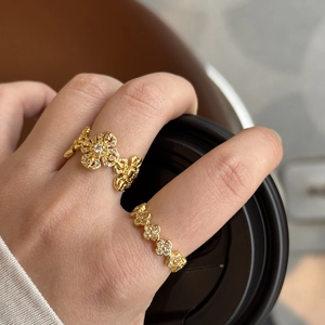 Detail of stacked gold flower rings with clear zircon stones on a model's hand