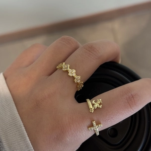 Detail of gold rings with zircon clover pattern and cross motif on a hand