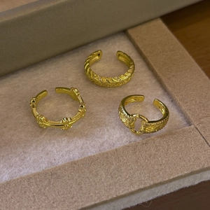 Detailed view of three adjustable gold-plated rings with zircon inlays and cross relief