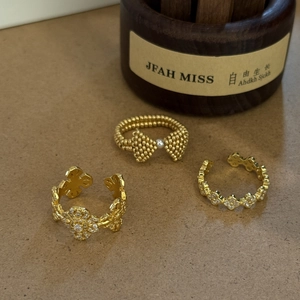 Detailed view of three-piece gold rings set featuring pearl bow and floral cutouts