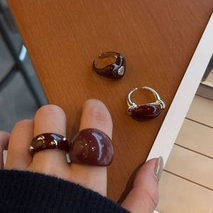 Close-up of burgundy enamel rings with silver accents and heart zircon details