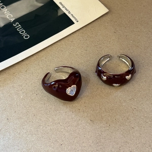 Vintage burgundy enamel heart rings with clear zircon stones on stylish magazine background