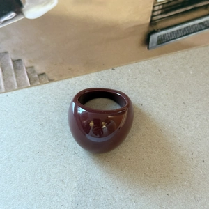 Detail of a wide dome ring in polished burgundy enamel with a sleek mirror finish