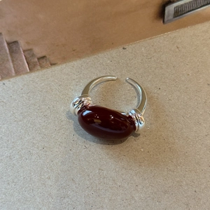 Detail view of adjustable silver ring with a large oval dark red enamel heart stone