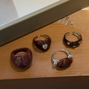 Close-up of burgundy enamel heart rings set with copper zircon on a warm wooden base