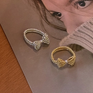 Detail of beaded bow rings in gold and silver set with tiny center pearls on magazines