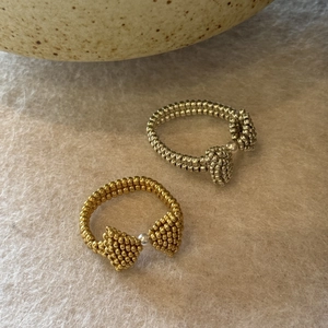 Detailed macro view of gold and silver beaded bow rings with delicate pearl centers