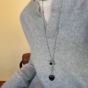 Long collier pull élégant argenté avec pendentif coeur noir porté sur un pull en maille