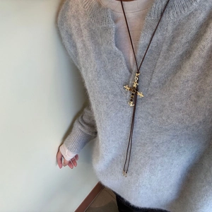 Vintage tijgeroog kruisketting met gouden hanger gedragen op grijze trui