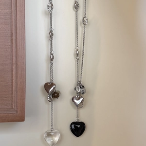 Détail de colliers en chaîne argentée avec des pendentifs en forme de cœur variés