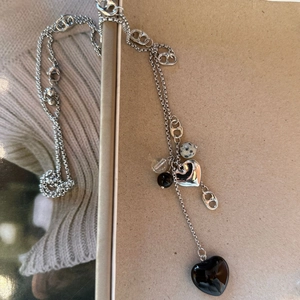 Détail du long collier argenté avec pendentif cœur noir et maillons créatifs style anneau