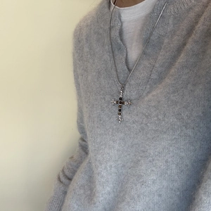Detailopname van vintage tijgeroog steen kruis ketting op een grijze trui