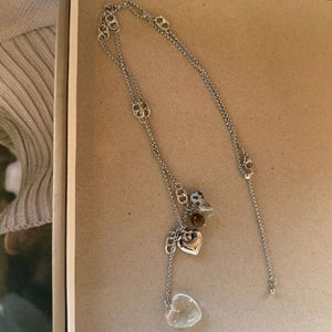 Détail d'un long collier argenté avec pendentif coeur et perles de pierre sur fond neutre