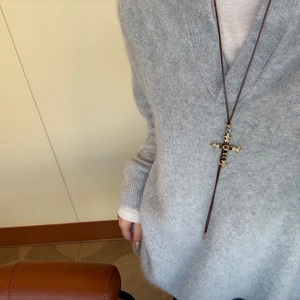 Vintage tijgeroog kruis ketting met gegraveerde metalen details op grijze trui