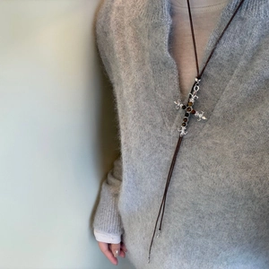 Close-up van vintage tijgeroog kruis hanger ketting gedragen op een grijze zachte trui