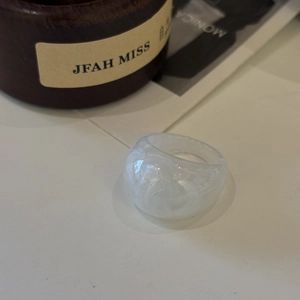 Close-up of translucent white resin ring with marble texture on wooden backdrop