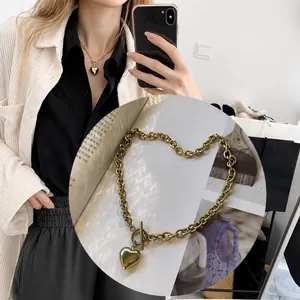Detalle del collar con colgante de corazón con cadena gruesa y cierre de barra en T