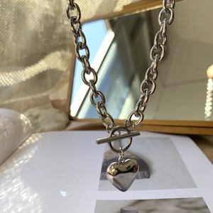 Detalle del collar de corazón plateado con cadena de eslabones y cierre de barra
