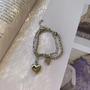 Vista detallada de una pulsera de plata de doble capa con corazón y cadena de clips
