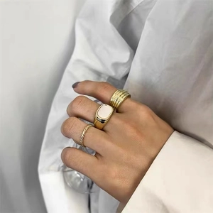 Detail view of stacked gold titanium steel rings with shell design on model hand