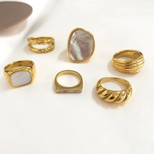 Macro view of gold plated titanium steel rings with white shell inlays and twisted details