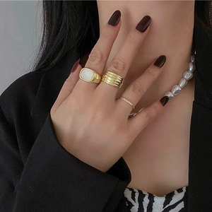 Macro detail of geometric gold rings and baroque pearl necklace styled with a black suit