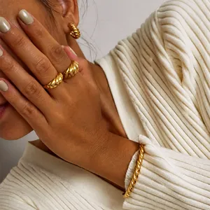 Close-up of golden croissant twist ring and jewelry set on a model with knitwear background