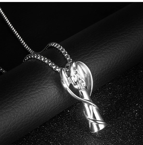 Gros plan du pendentif aile d'ange en argent avec chaîne box sur fond en cuir noir