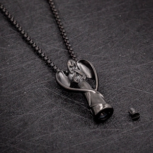 Détail macro du pendentif urne funéraire en acier noir en forme d'aile d'ange sculptée