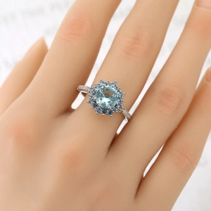 Luxury sunburst light blue gemstone ring with halo diamonds on polished silver band