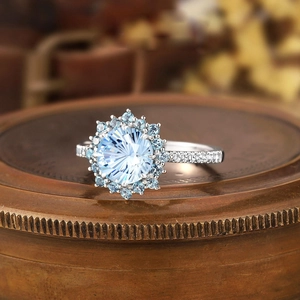 Elegant light blue round crystal ring in silver halo setting on a vintage copper box