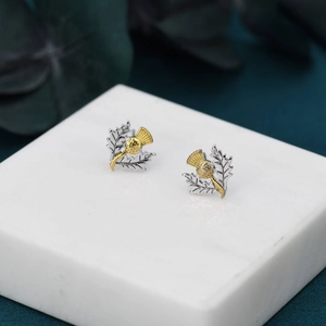 Orecchini a perno con cardo scozzese vintage bicolore oro e argento su base di marmo
