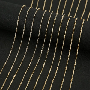 Macro detail of gold-plated copper satellite chain necklaces on black display stand