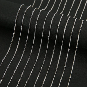 Detailed macro view of multiple silver satellite beaded chains on a black jewelry display