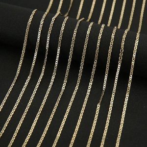 Macro detail of polished gold-plated mariner link chains on a black velvet display