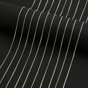 Macro shot of silver plated box chain necklaces displayed on black jewelry stand