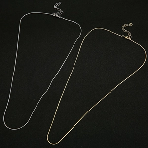 Close-up of gold and silver snake bone chains with lobster clasps on black background