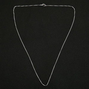 Detail of silver box chain necklace with durable lobster clasp on textured surface