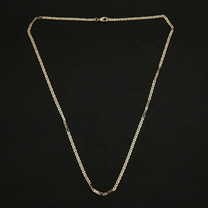 Flat snake bone chain necklace in gold finish with lobster clasp on black background