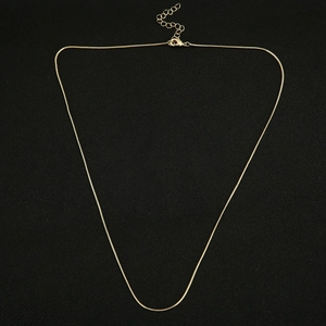 Detail of a shiny gold-plated snake chain necklace with lobster clasp and extension